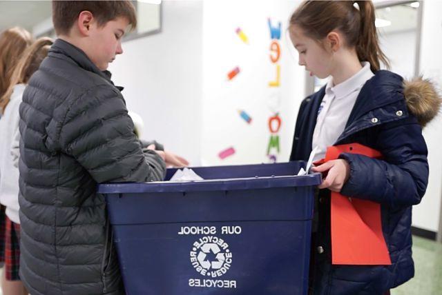 Girl and boy student holding recycling can